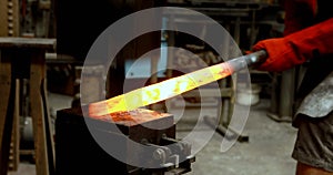 Blacksmith shaping hot metal rod in machine 4k