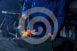 Blacksmith using heavy hammer for forging molten metal