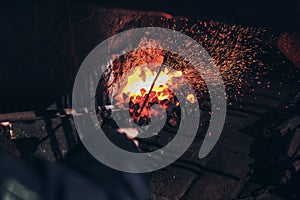 Blacksmith at work with glowing irons.