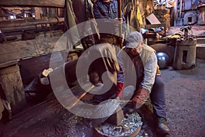 Blacksmith workers using mechanical hammer at workshop