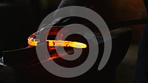 Blacksmith working with hot glowing metal, bending steel in a smithery photo