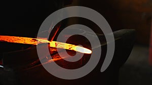 Blacksmith working with hot glowing metal, bending steel in a smithery photo