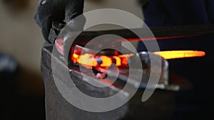 Blacksmith working with hot glowing metal, bending steel in a smithery, slow motion