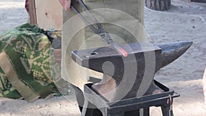 Blacksmith working with an iron details in his workshop - hitting the metal piece with a hammer. Concept: industry