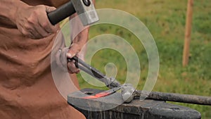 Blacksmith working with metal on anvil outdoor - slow motion, close up