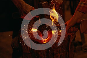 Blacksmiths hit molten metal with hammers close up