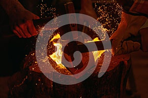 Blacksmiths hit molten metal with hammers close up