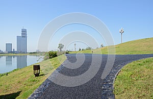 Blacktopped path on grassy lakeside in sunny summer morning photo