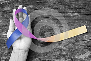 Bladder cancer awareness marigold blue purple  ribbon color splashed on helping hand, old aged background