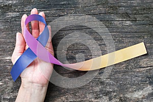 Bladder cancer awareness marigold blue purple  ribbon on helping hand suport isolated with clipping path