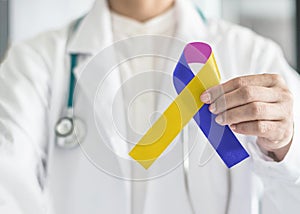 Bladder cancer awareness marigold blue purple ribbon symbolic bow color on in doctor hand to support patient with tumor illness