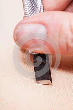 Blade of swivel knife cut leather surface close up
