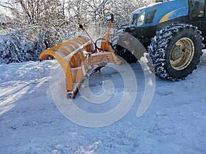 A blade tractor pushes the snow off the road
