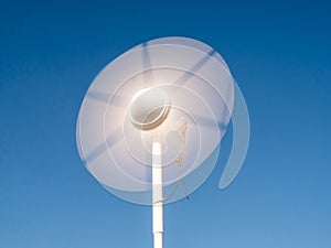 Blades of white wind turbine turning against a blue sky, sustainable energy for boating