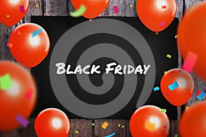 Blak Friday sale concept with text on black paper surrounded with red ballons and confetti