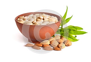 Blanched almonds In a bowl with unshelled nuts. On white background.