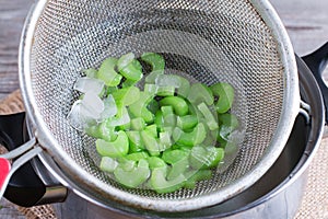 Blanched celery in a colander in ice water