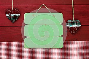 Blank antique green wooden menu sign with holiday hearts and red gingham tablecloth