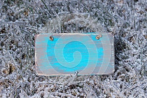 Blank antique wooden sign with ice covered grass background