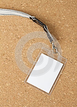 Blank badge with neckband on corkboard background.