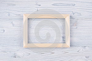 Blank beige wood frame on light blue wooden board. Copy space, top view.
