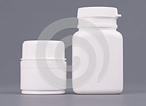 Blank big and medium size medicine white plastic packaging bottles for cosmetics, vitamins, pills or capsules. Packaging