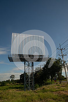 Blank billboard on the background of the road and blue sky.