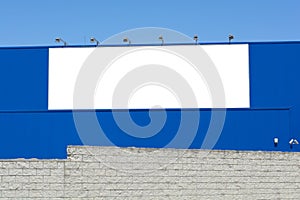 Blank billboard on brick and blue wall, banner edge and grommets preserved