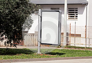 Blank billboard with copy space for your text message or content, public information board on flowerbed with green grass.