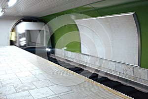 Blank billboard on green subway wall and mooving train