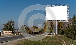 Blank billboard sign by empty highway through mountains landscape.