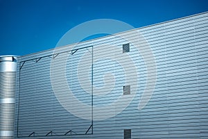 Blank billboard steel frame on facade of industial style building under blue sky