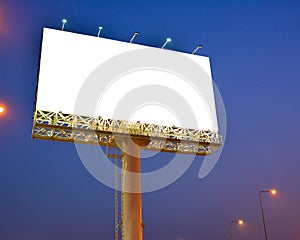 Blank billboard with white screen against blue sky at twilight time background. Copy space banner for advertisement.