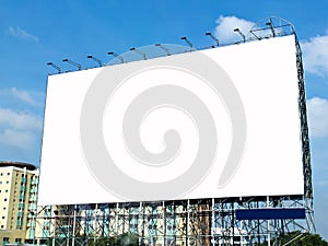 Blank billboard with white screen against clouds and blue sky background.