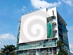 Blank billboard with white screen against clouds and blue sky background.