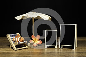 Blank black board with beach umbrella and bed with clown fish and flower
