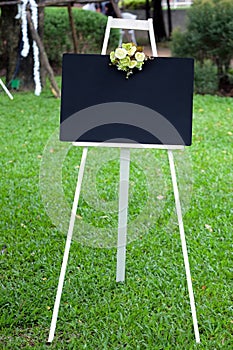 Blank black board with flower on the stand in the garden.