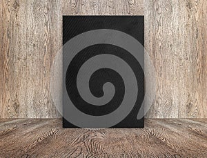 Blank black canvas poster leaning at wood wall on wooden floor i