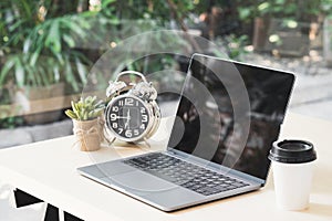 Blank black laptop screen display on wooden table with a cup of