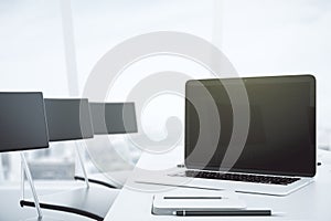 Blank black laptop screen on white table in conference room with