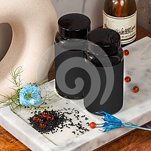 Blank black plastic jar with red caraway oil capsules and black seeds in bathroom