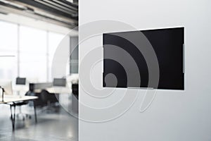 Blank black poster with space for your logo or advertising text on light grey wall background in modern office area with blurred