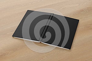 Blank black vertical open and upside down book cover on wooden background isolated with clipping path around cover.