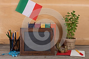 blank blackboard, flag of the Italy, books, chancellery on table and wooden background