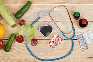 Blank blackboard in shape of heart, stethoscope and choice between natural vitamins, vegetables, fruits and berries or tablets and