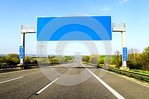 Blank blue freeway sign over the road on sunny day