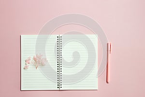 A blank book with pink flower and pen over the pink background.