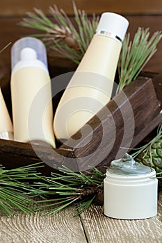 Blank bottle packaging with natural cosmetic cream, serum, skincare, lotion, tonic with forest coniferous branches and cones on