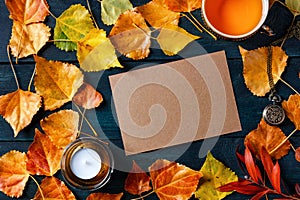 A blank brown craft greeting card or invitation with a cup of a tea, autumn leaves and a candle, an autumn stationery