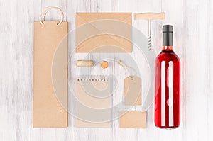 Blank brown kraft packaging, stationery, merchandise set with bottle rose wine on soft white wood background.